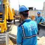 Construction workers operating excavator at a road site, ensuring progress and safety.