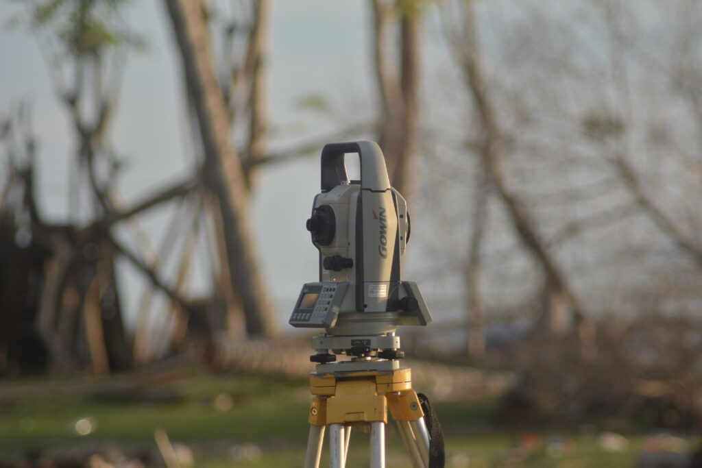 A precise total station used for geodetic surveying at a construction site with a natural background.